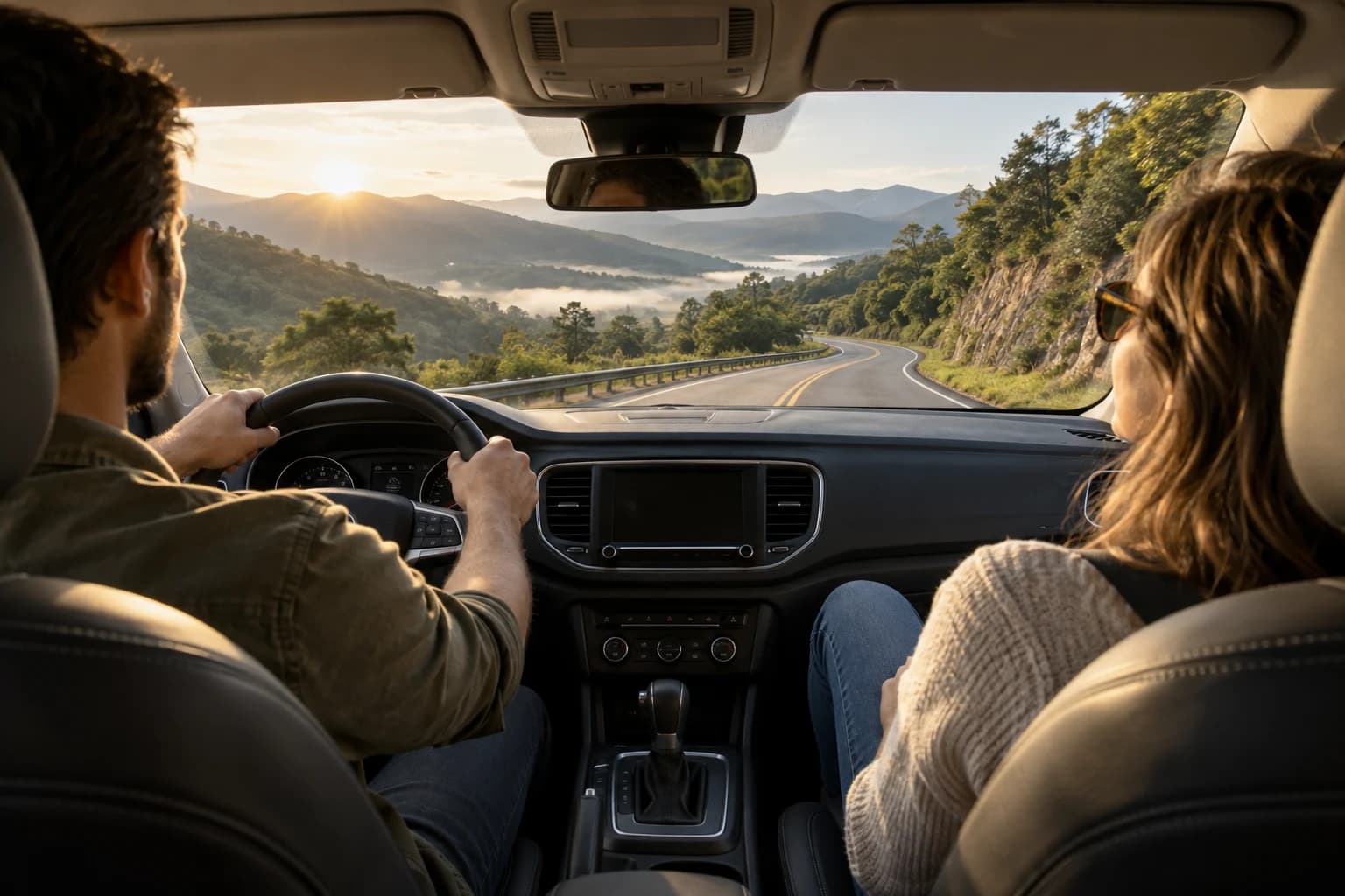 A couple wearing seat belts on a mountain road; the driver is paying attention to the road